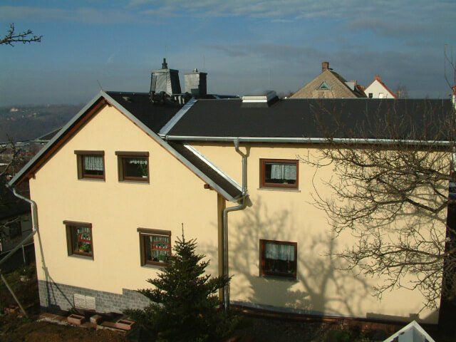 Gelbes Haus mit neuem dunklen Dach und Kamin