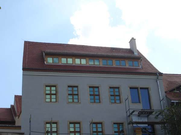 Graues Gebäude mit neuem rotem Ziegeldach und Dachfenstern