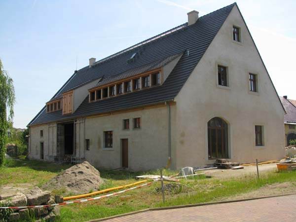 Haus mit neuem dunklem Zeltdach und Dachfenstern im Rohbauzustand, Gutshofgebäude in Pratzschwitz